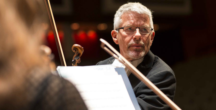 RPO Player Duncan Riddell holding his violin and looking to his left.