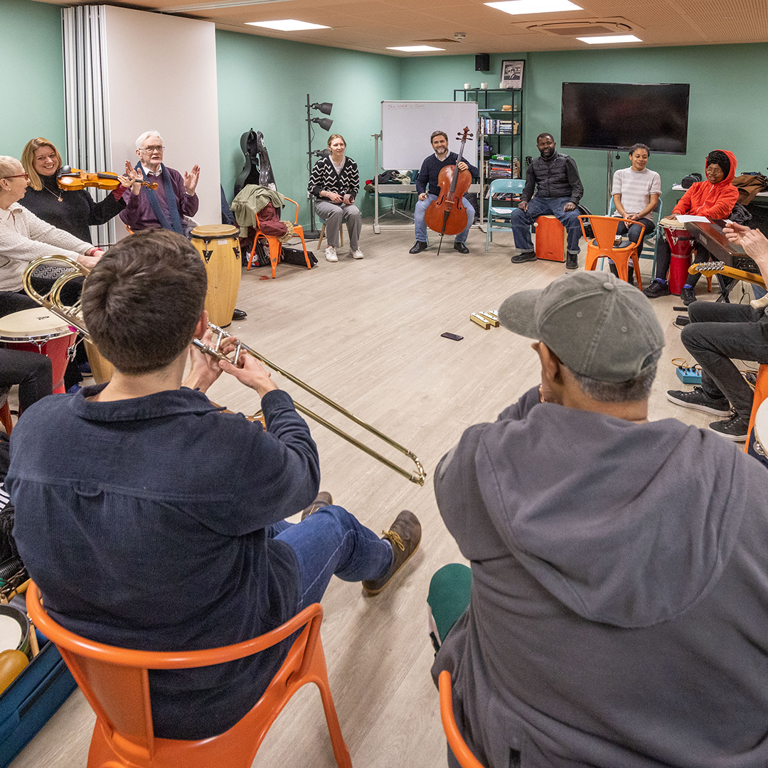 Participants in a Brent Sound Sanctuary session playing instruments in a circle with RPO musicians