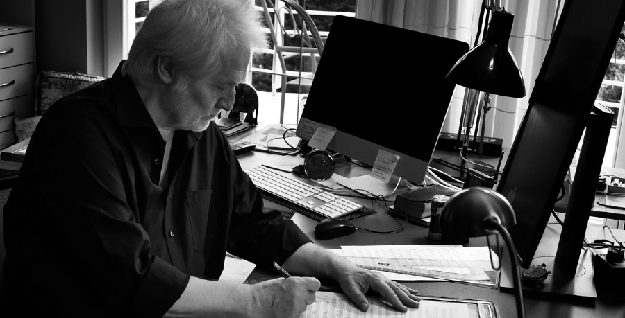 Péter Eötvös sitting at his desk and writing on a score